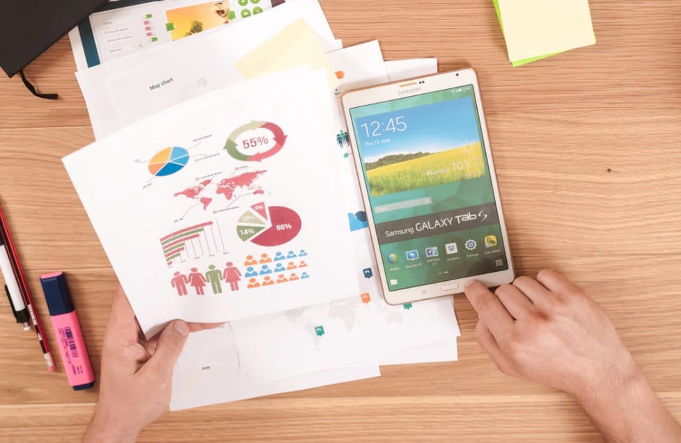 image of different types of pivot charts printed out with a phone and hands on a table.